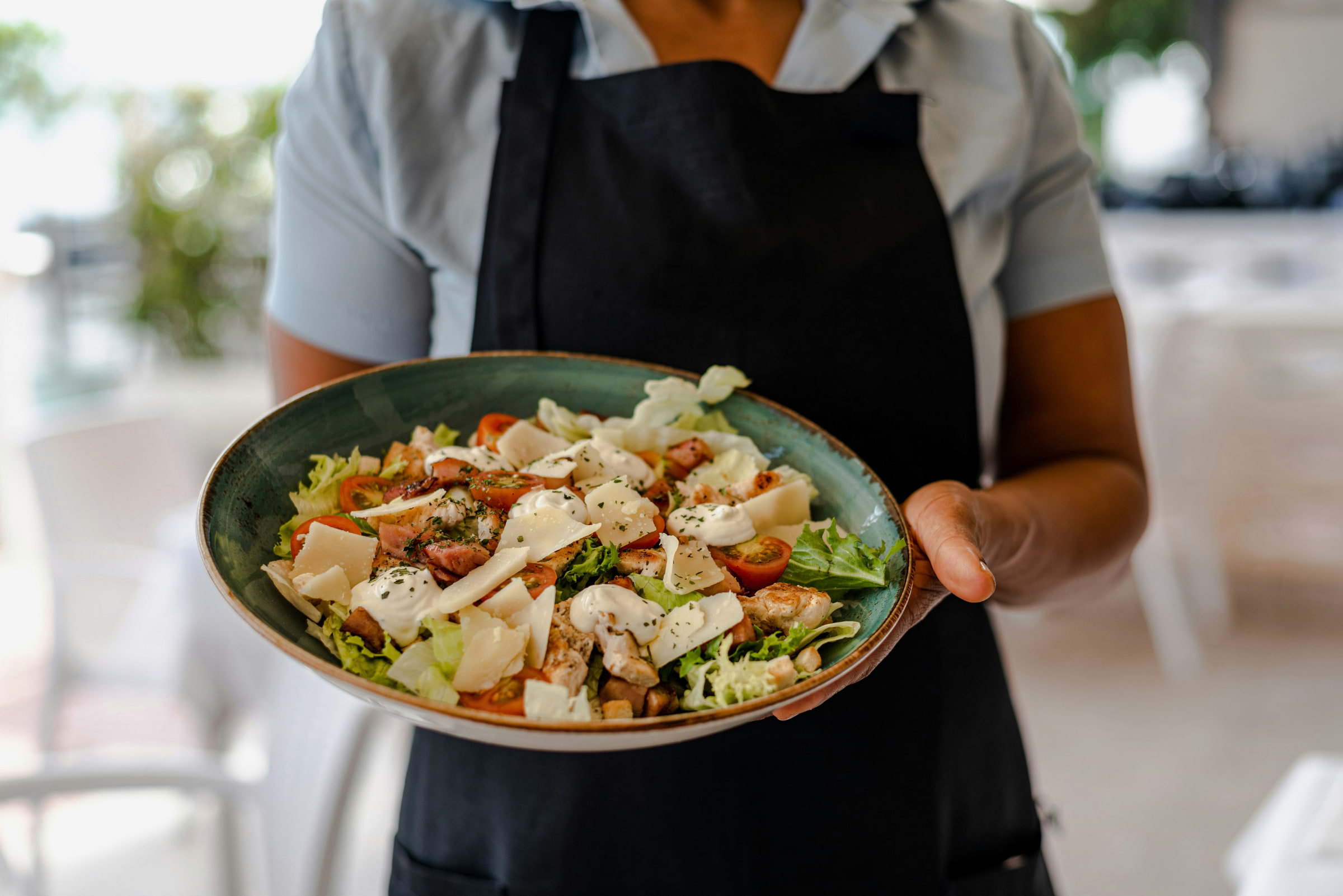 A person holding a big bowl of salad