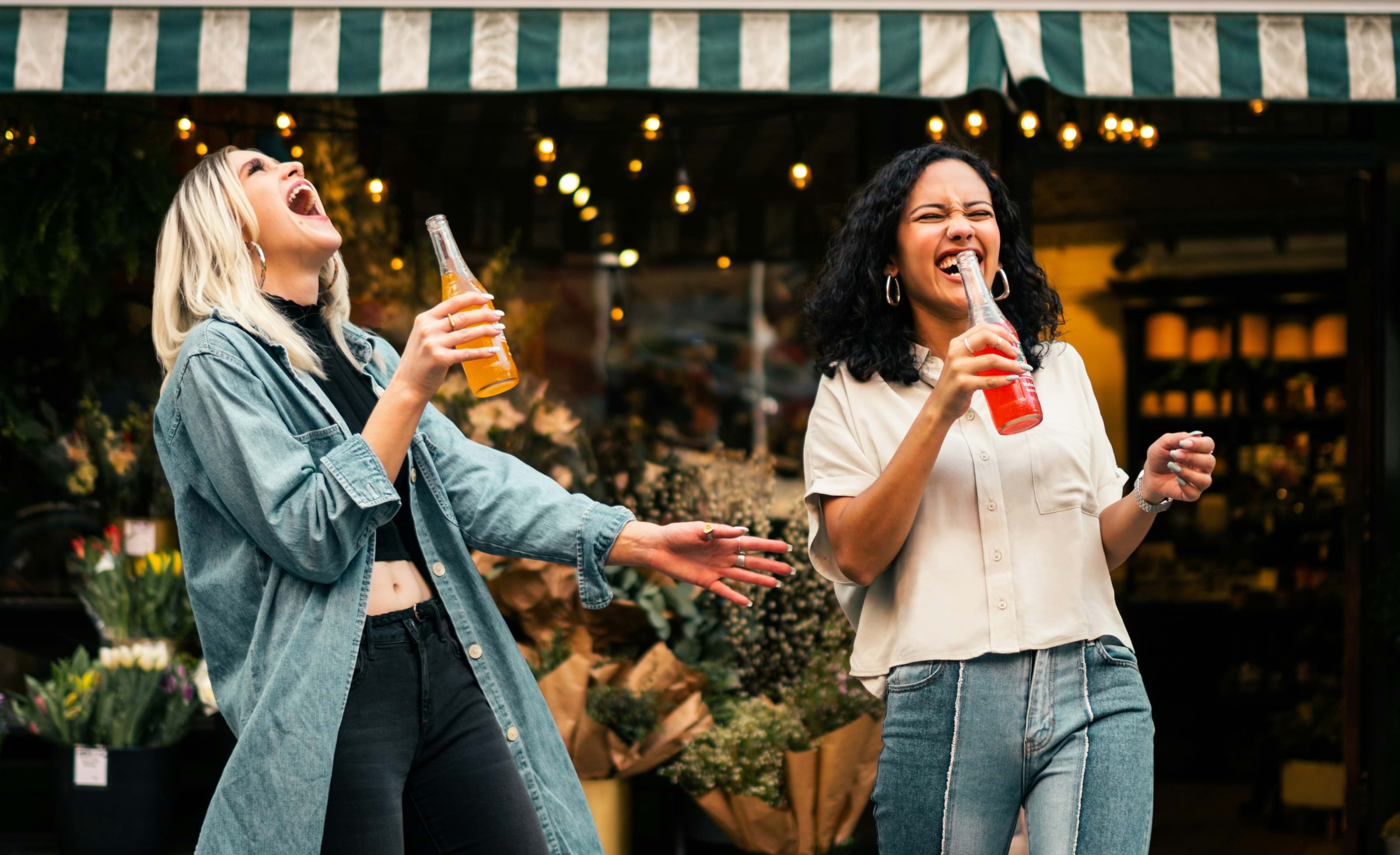 Two women laughing and drinking outside