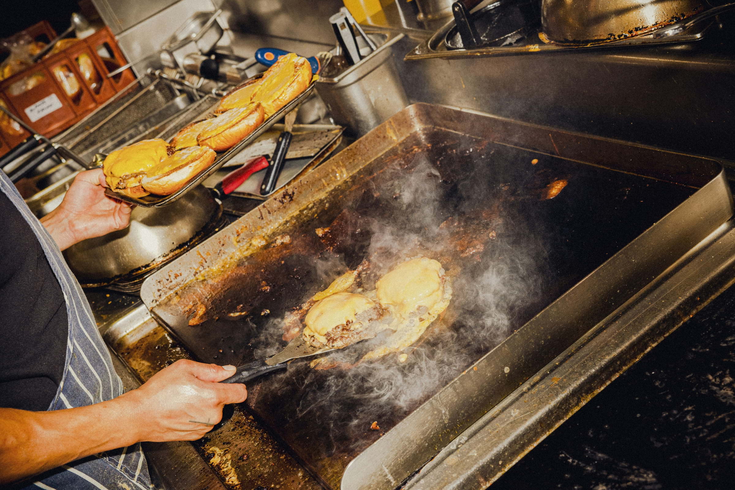 Burgers being cooked on a flat silver grill