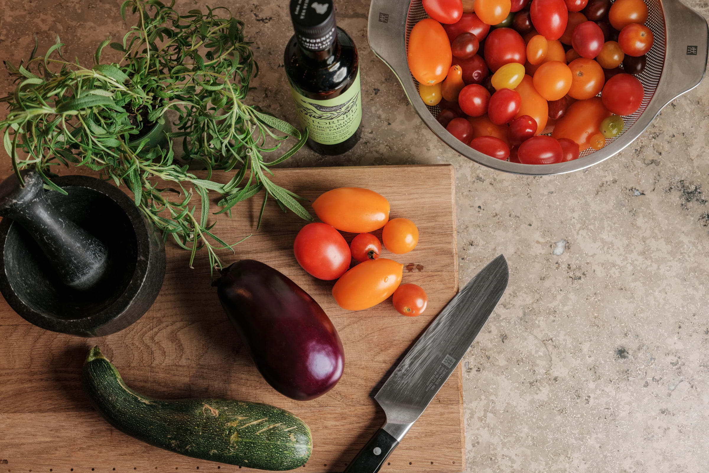 Different vegetables and a knife laid out on a wooden cutting board