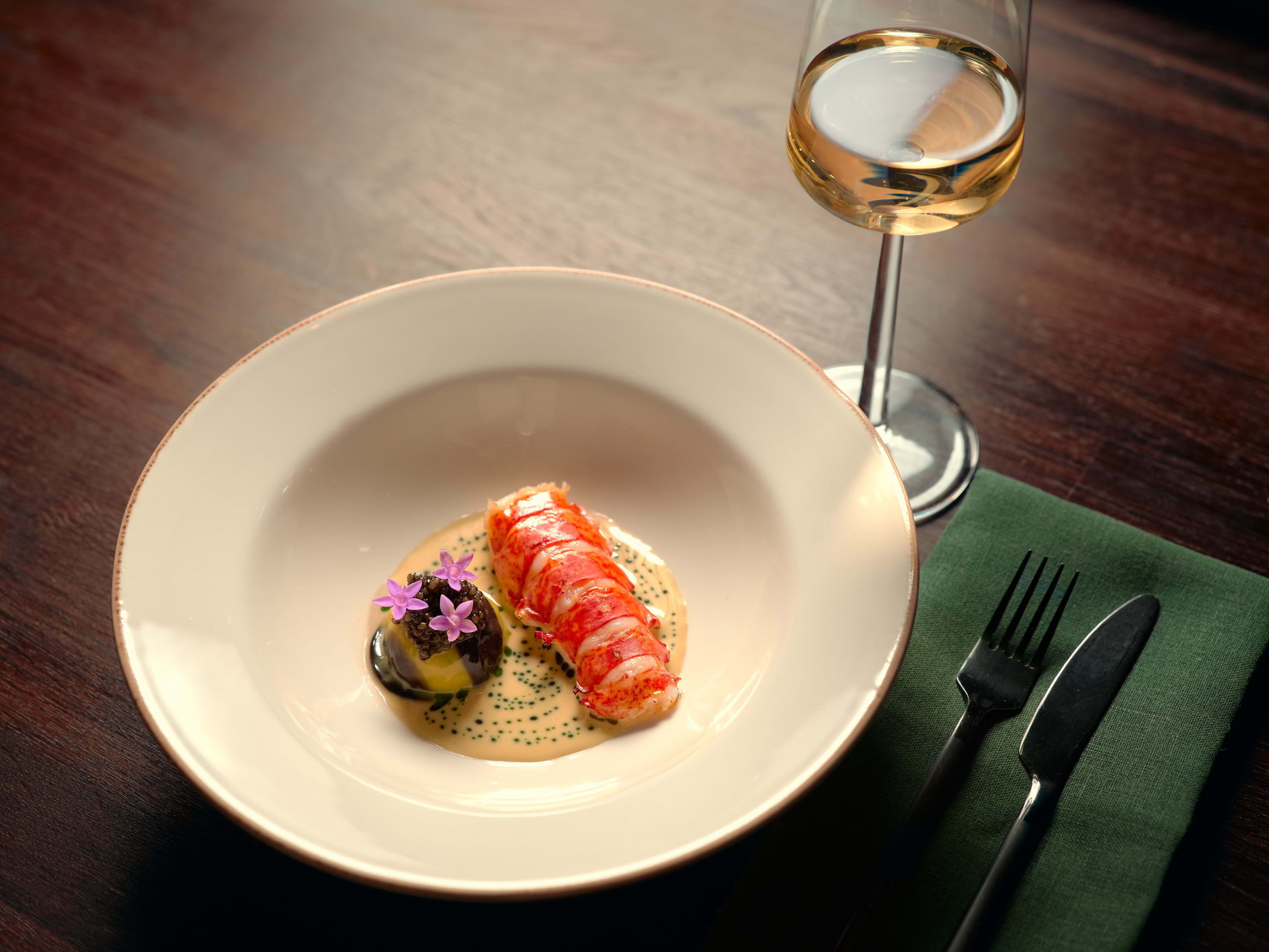 A colourful fine-dining dish on a simple white plate in a restaurant