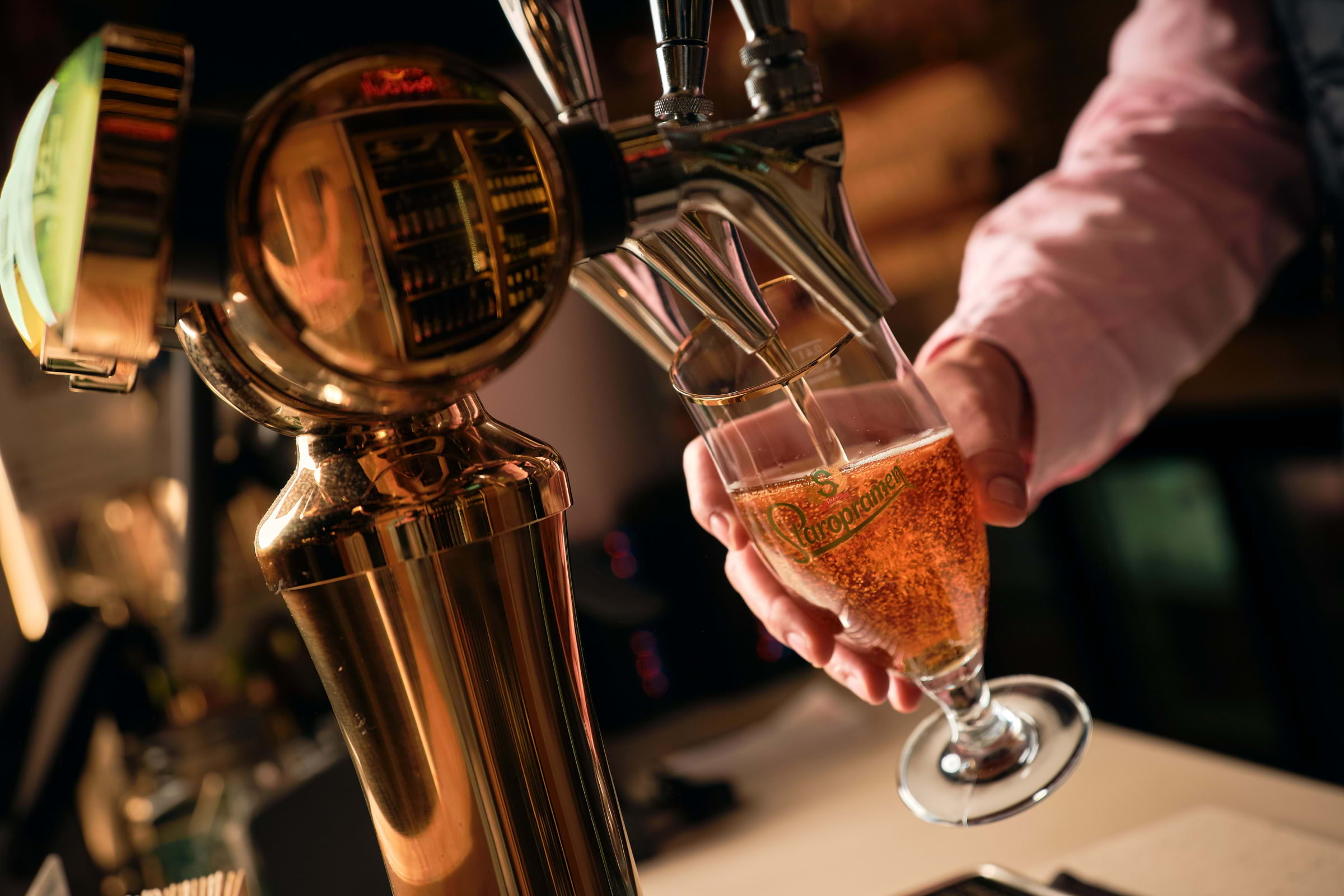A bartender pouring a pint of beer from a tap in a pub