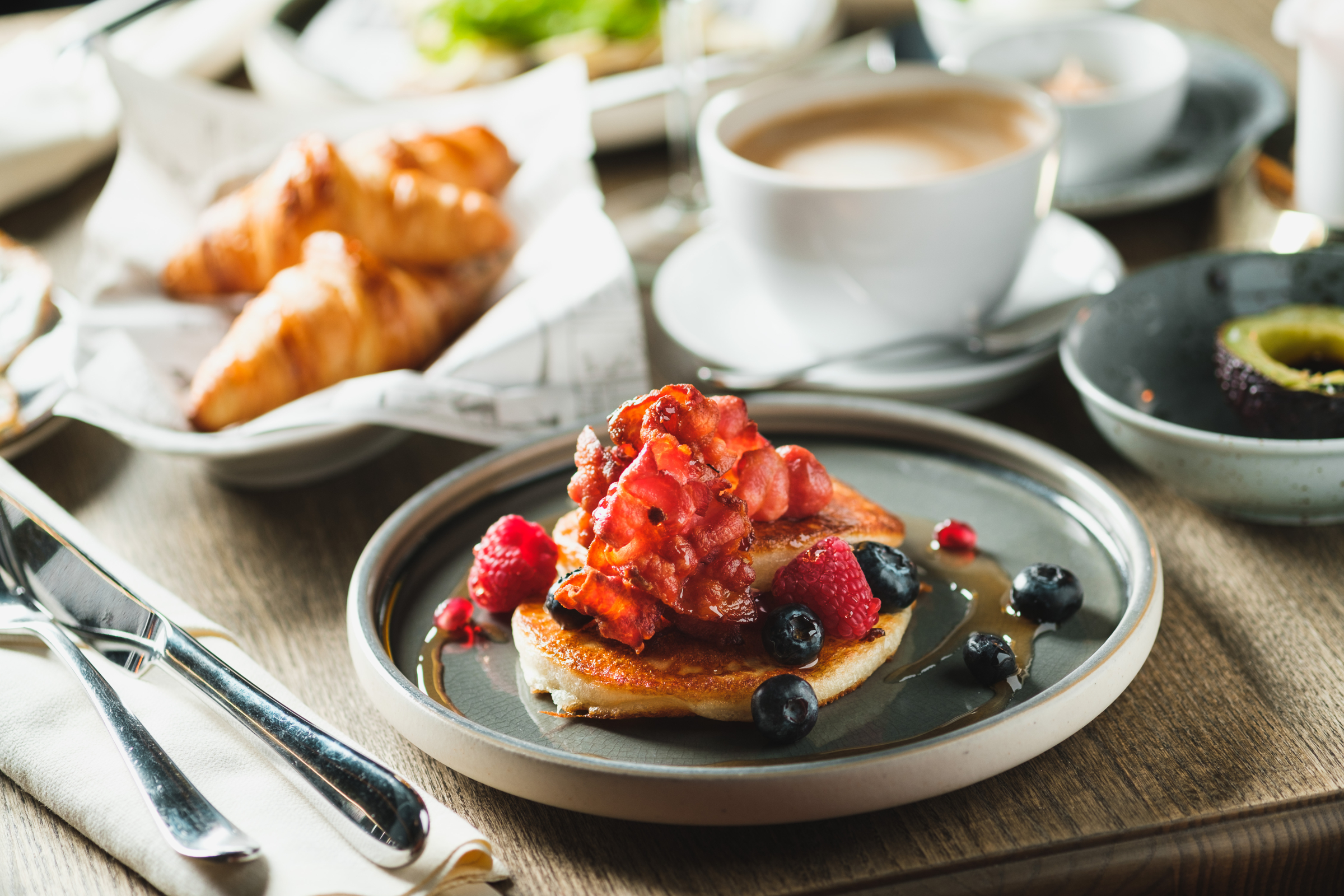 Amerikanske pandekager serveret til brunch med croissanter, kaffe og avocado i København.