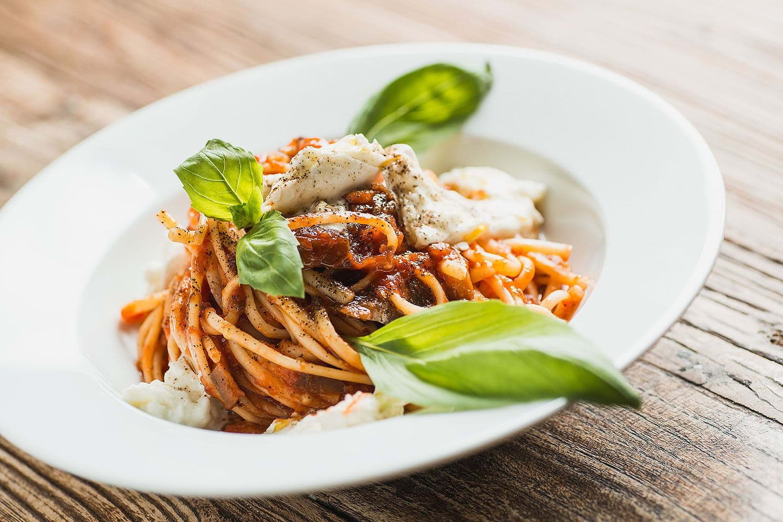 A spaghetti dish on a white plate in a restaurant