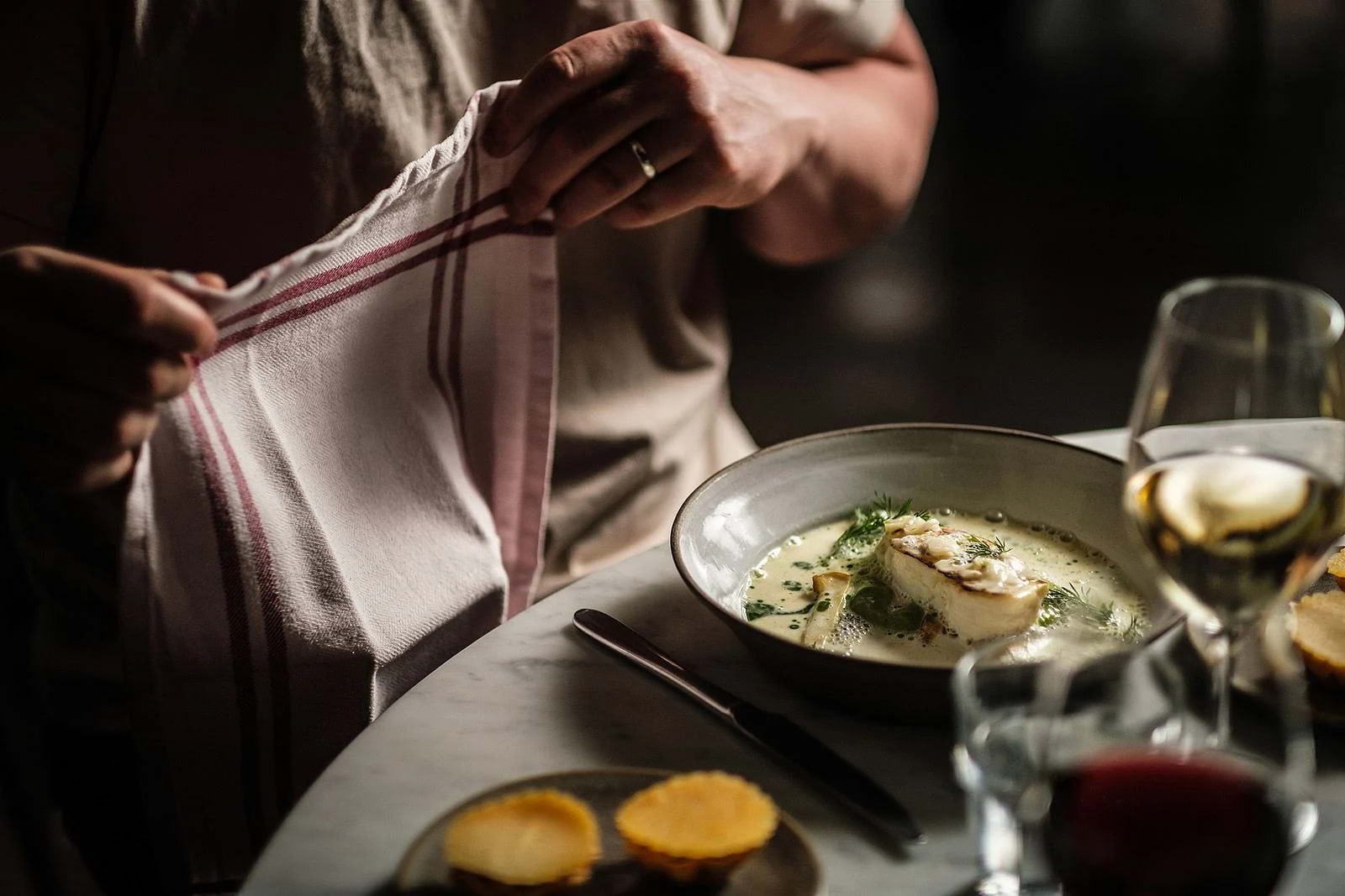A diner at a restaurant placing a cloth napkin on his lap