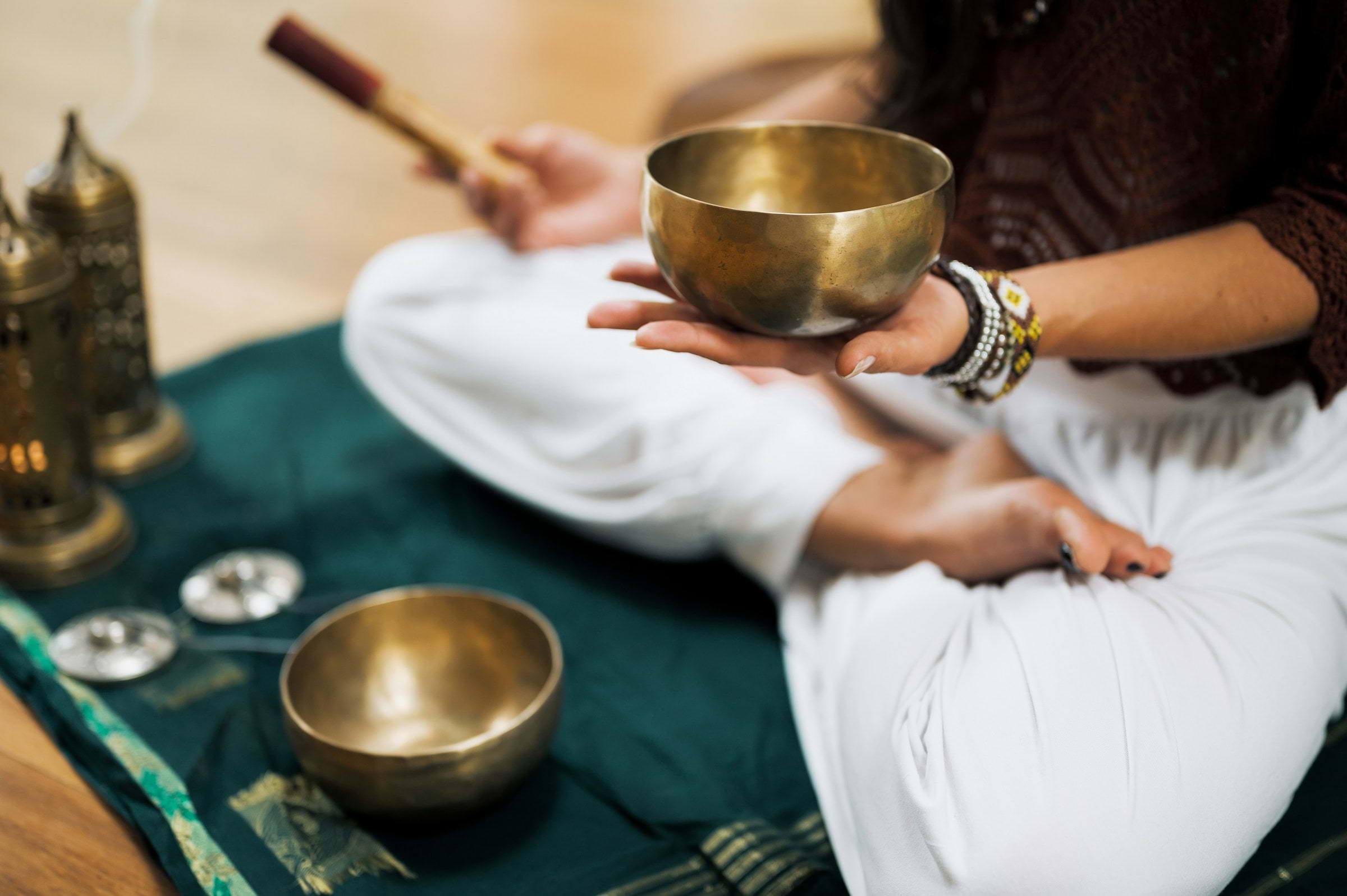 A sound bath practitioner holding a gleaming metal bowl