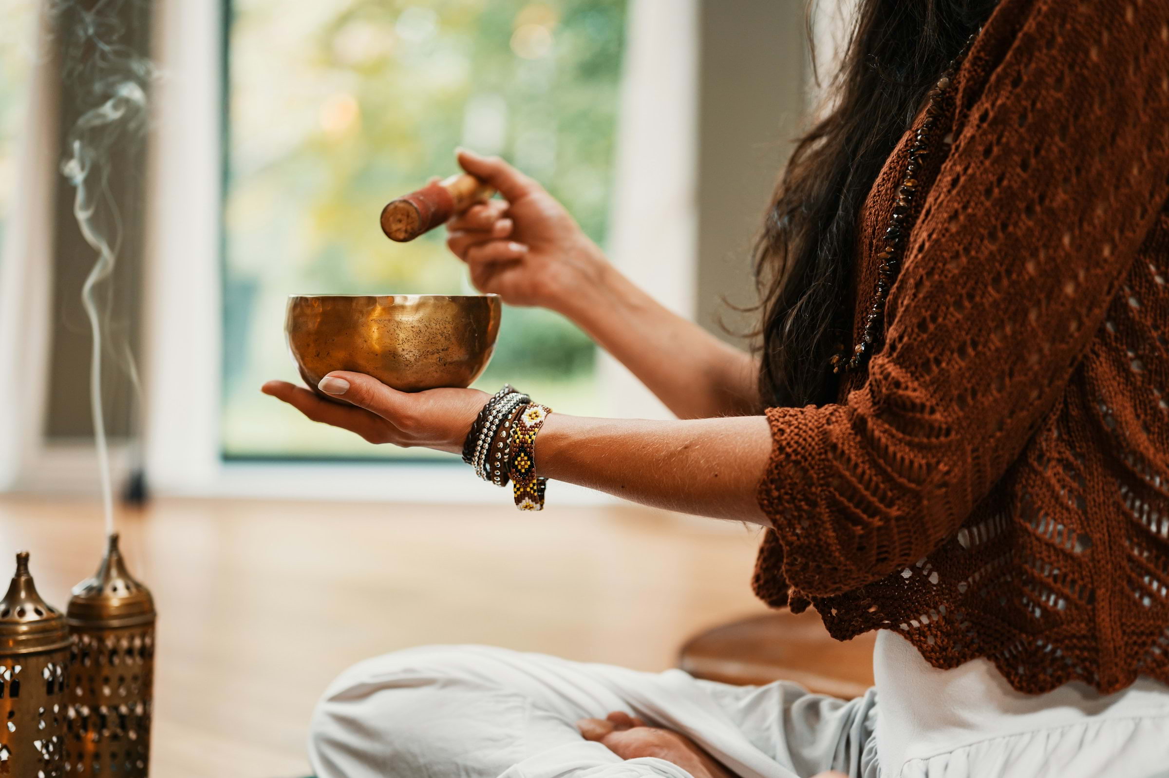 A sound bath practitioner holding a gleaming metal bowl
