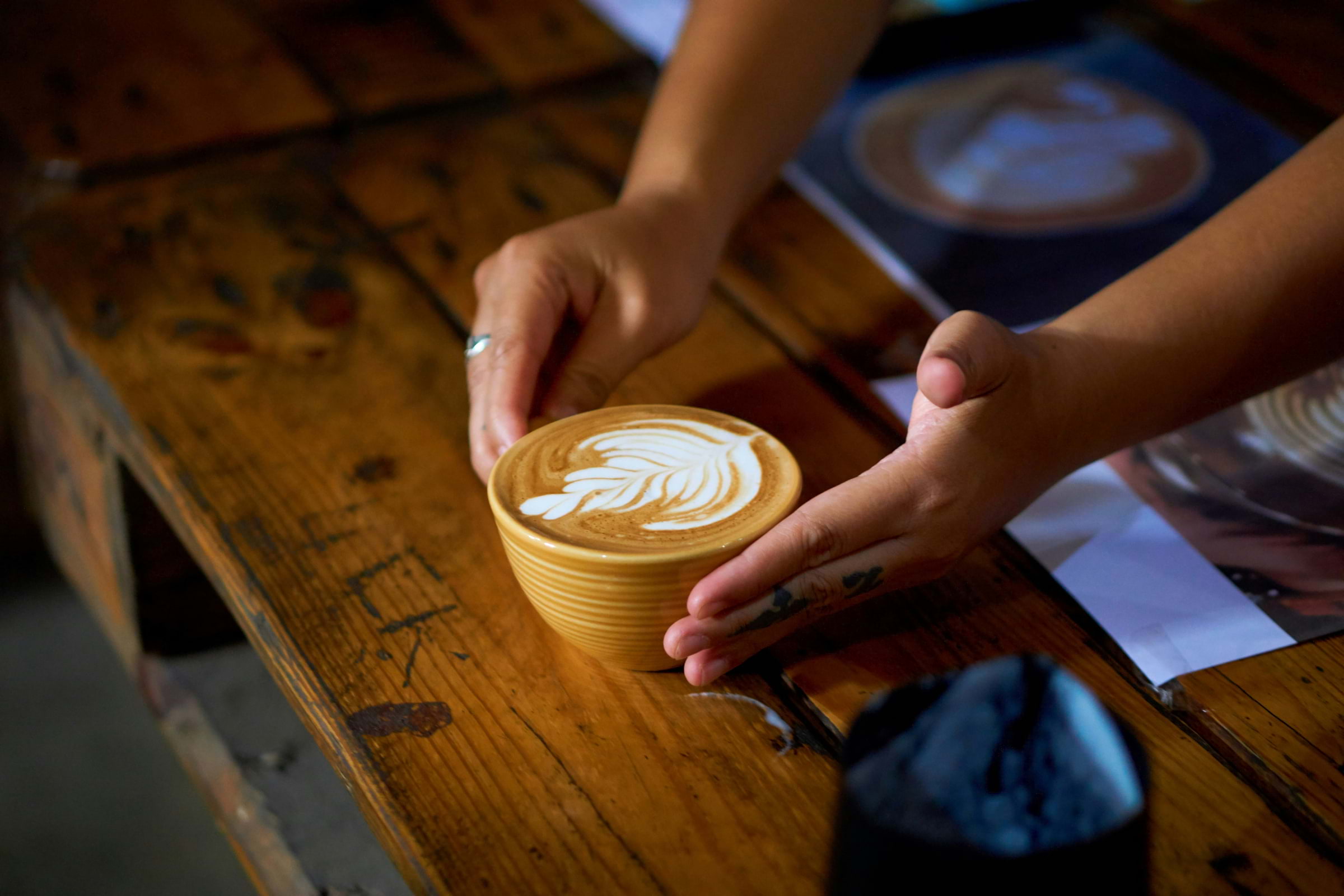 A person holding a yellow coffee cup with latte art