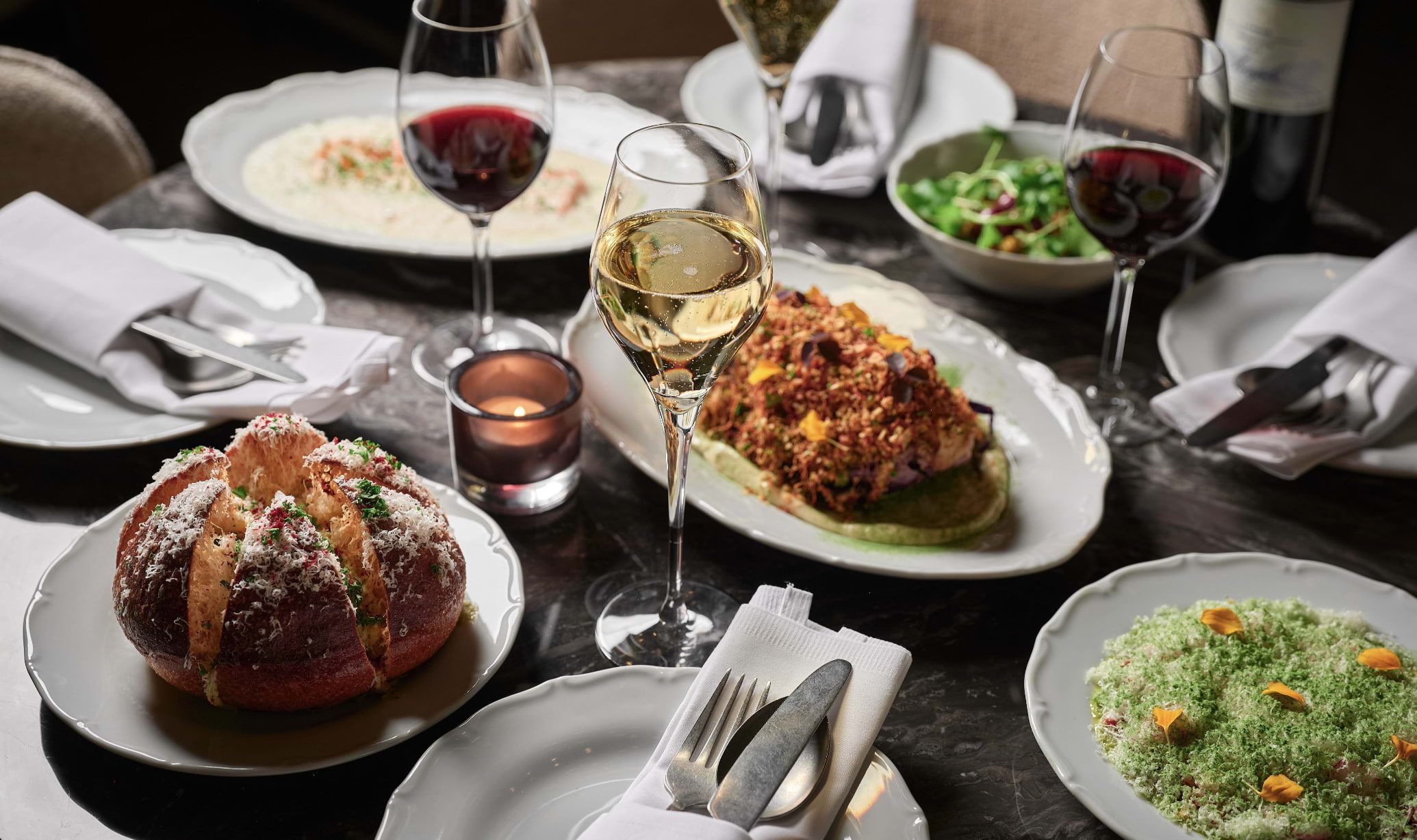 Restaurant table laden with dishes and full glasses of wine