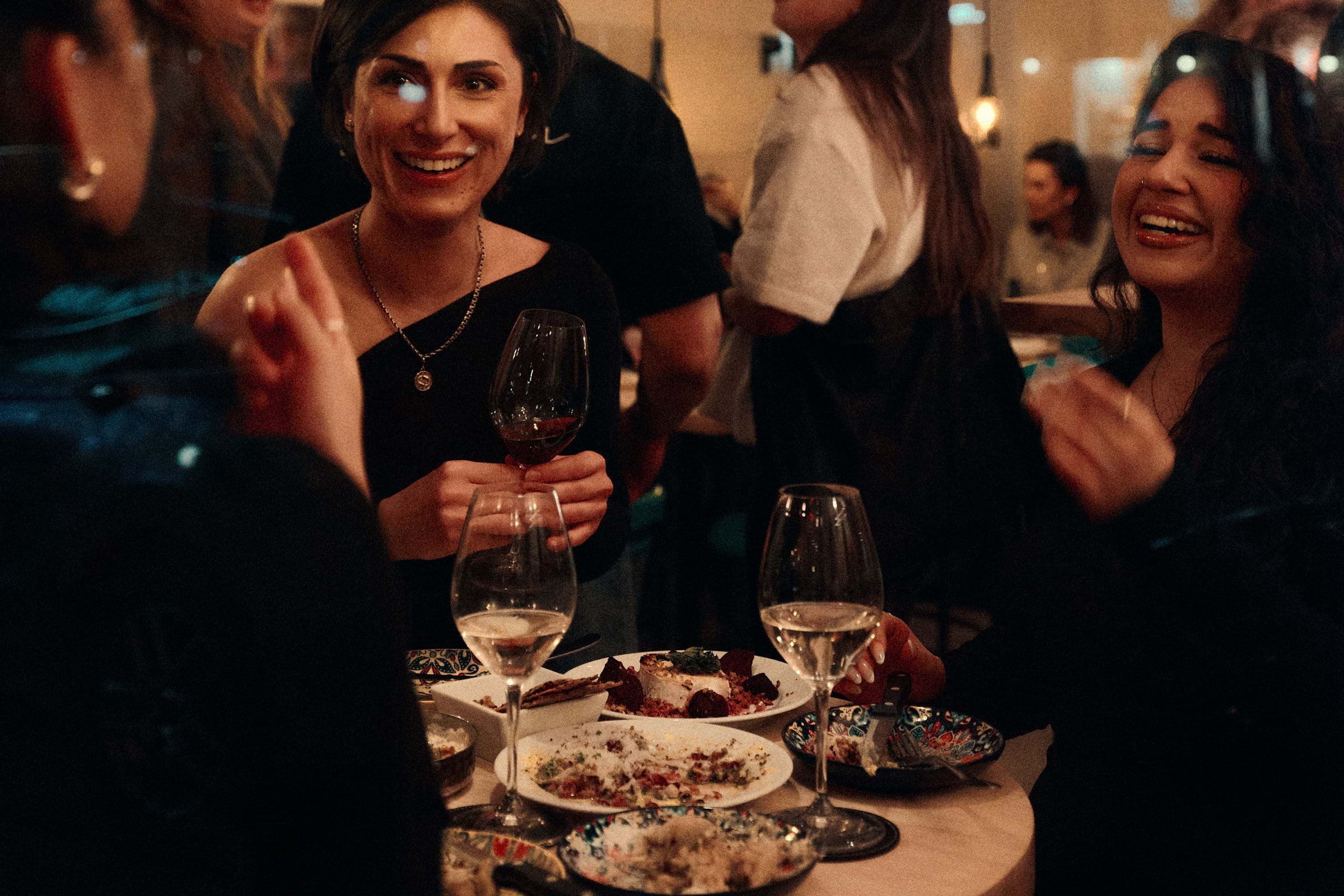 Three women enjoying small plates and wine at a restaurant in the evening