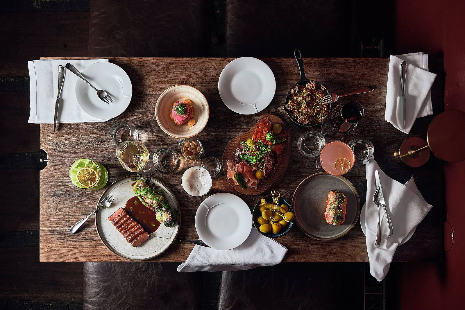 A bird's-eye view of a wooden restaurant tables covered with dishes and drinks