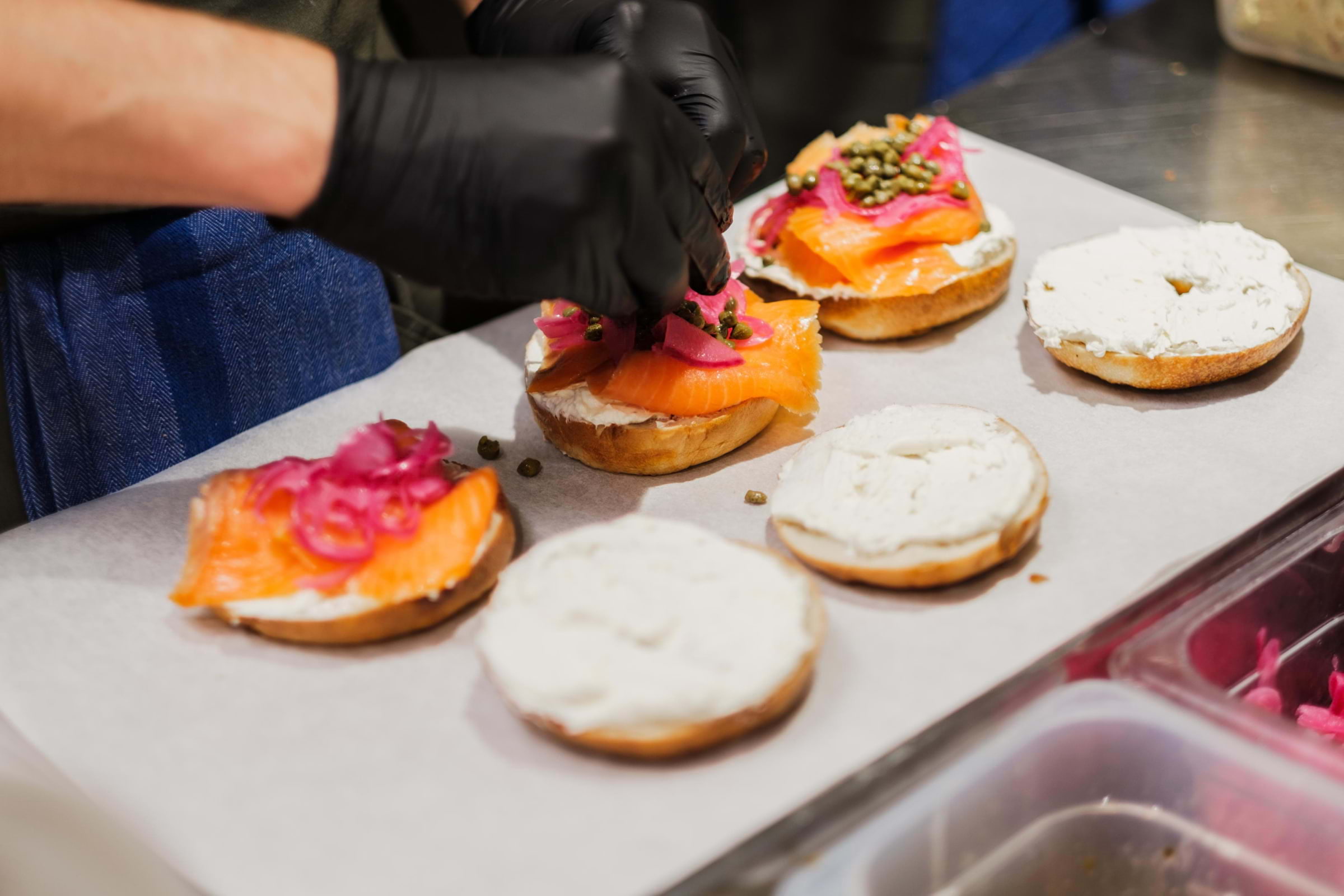A chef putting toppings on bagels