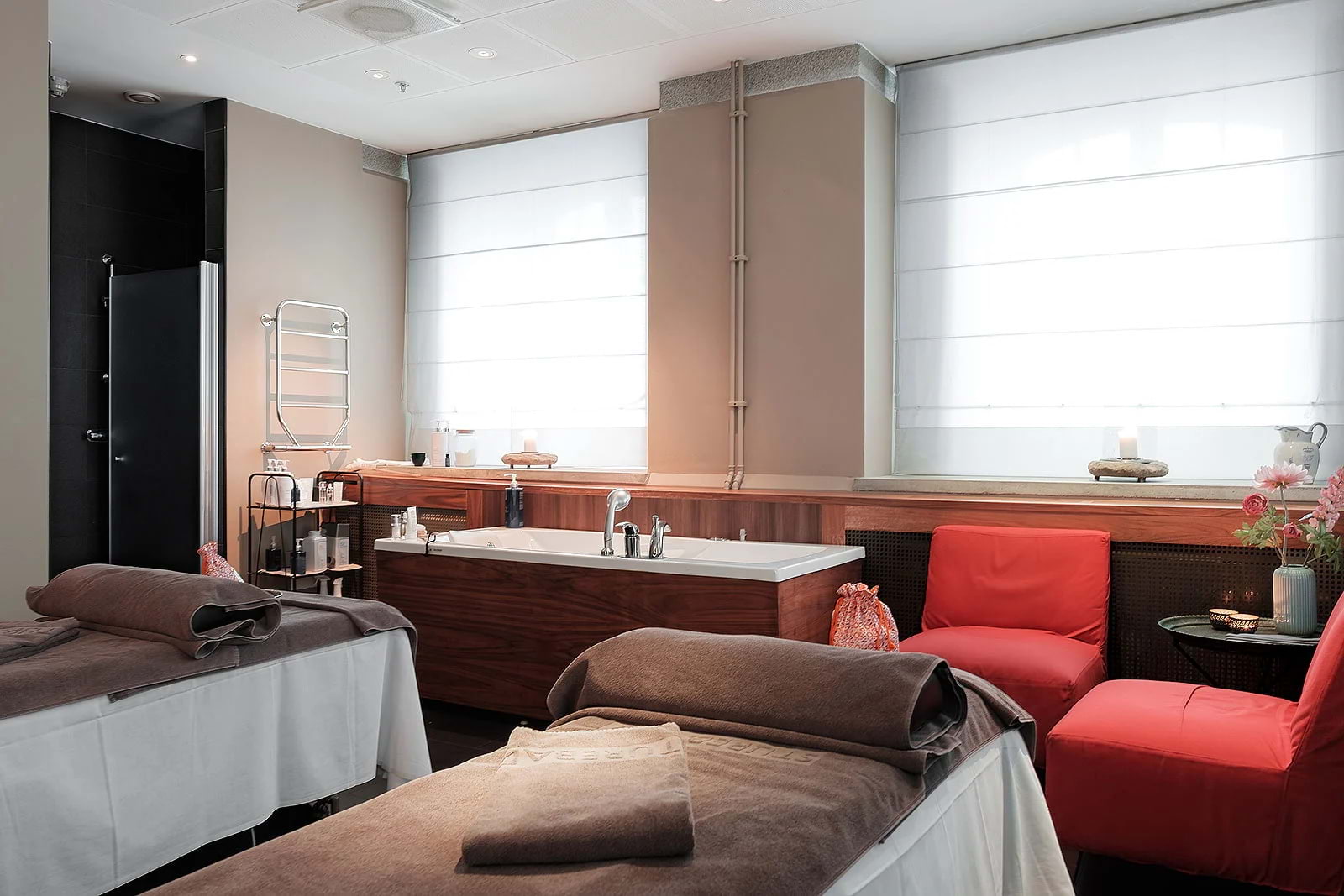 Two massage tables in a massage studio with white walls and red seating
