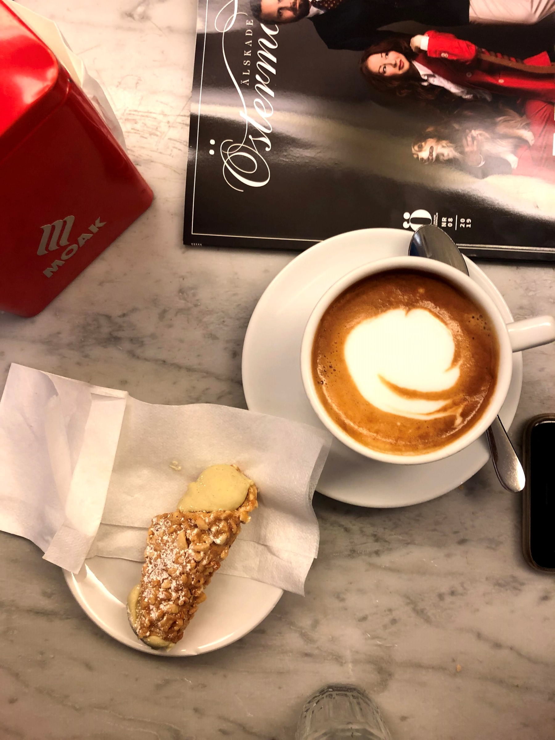 Cappuccino med klassiskt Italienskt kondis bit  – Bild från Sempre Espresso Bar av Madiha S. (2020-05-27)